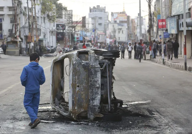 A boy walks past a vehicle burnt by a mob during a protest against Thursday's attack on a paramilitary convoy, in Jammu, India, Friday, February 15, 2019.  Thursday's attack on a paramilitary convoy in Kashmir has raised tensions in Hindu-majority India. Hundreds of residents carrying India's national flag in Hindu-dominated Jammu city in the Muslim-majority state burned vehicles and hurled rocks at homes in Muslim neighborhoods, officials said. (Photo by Channi Anand/AP Photo)