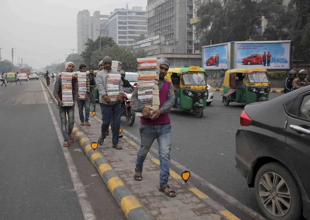 Indian street hawkers walk through a median as they sell pirated copies of books at a traffic intersection in New Delhi, India, Thursday, February 14, 2019. Though India has laws against copyright infringement, the rules are openly flouted. (Photo by R.S. Iyer/AP Photo)