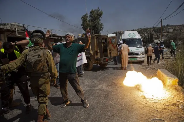 A sound grenade is fired by Israeli forces during a protest against the creation of a new road for Israeli settlers, near the Palestinian village of Beita, north of the West Bank city of Nablus, Wednesday, August 25, 2021. (Photo by Majdi Mohammed/AP Photo)