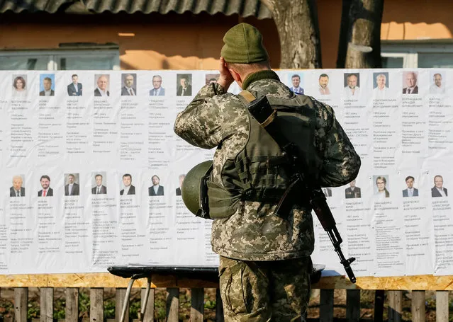 A Ukrainian serviceman reads information about presidential candidates at a polling station, created for the servicemen who take part in the government's five-year-old conflict in eastern Ukraine against Kremlin-backed rebels, near the front line, during a presidential election in the village of Zaitseve, Ukraine March 31, 2019. (Photo by Gleb Garanich/Reuters)