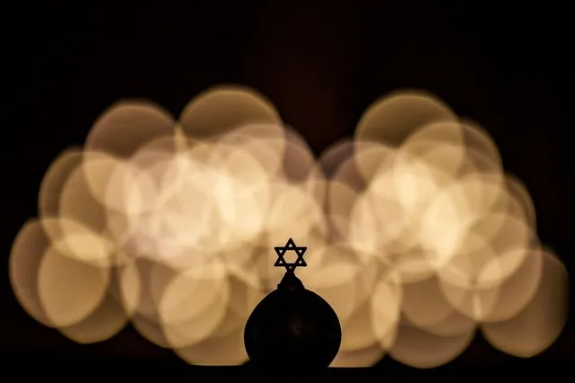 The Star of David is silhouetted against light installations during a memorial for the victims of the Holocaust, at the Coral Temple synagogue in Bucharest, Romania, Monday, January 29, 2024. (Photo by Andreea Alexandru/AP Photo)