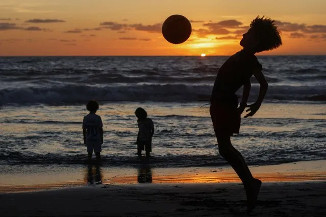 A child plays football against the setting sun, at a beach in the Kerobokan district of Indonesia's resort island Bali on December 19, 2023. (Photo by David Gannon/AFP Photo)