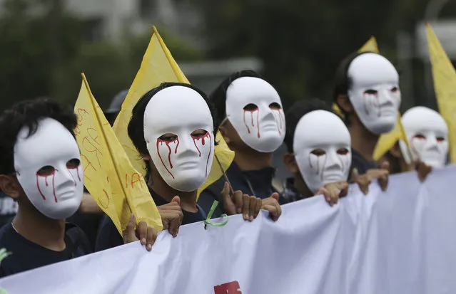 Workers wear masks during a May Day rally in Jakarta, Indonesia, Wednesday, May 1, 2019. Thousands of workers attended the rally urging the government to raise minimum wages, ban outsourcing practices, provide free health care and improve working condition for workers in the country. (Photo by Achmad Ibrahim/AP Photo)
