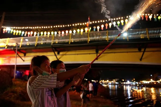 Children play with firework near a river, during the Loy Krathong festival which is held as a symbolic apology to the goddess of the river in Chiang Mai, Thailand, November 19, 2021. (Photo by Soe Zeya Tun/Reuters)
