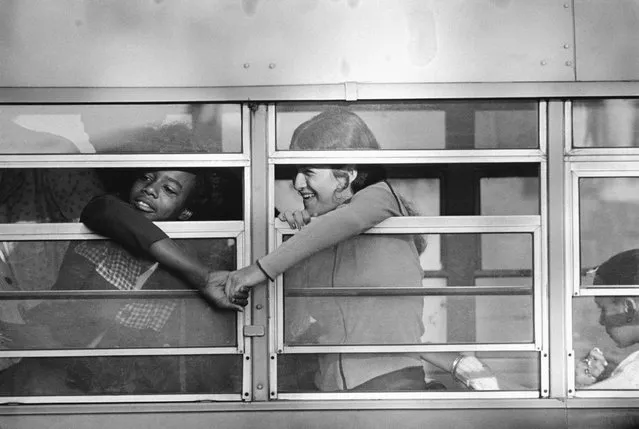 Boston:The second week of the phase 2 school integration of the Boston school system began 9/15 with security somewhat relaxed and no trouble reported. There was an apparent marked increase in attendance to the schools, sepecially true among whites previously boycotting classes. Here, a black and a white grasped hands through window as the bus pulled up in front of Charlestown High School. 9/15/1975. (Photo by Bettmann Archive/Getty Images)