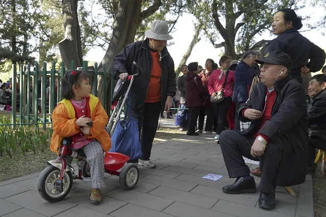 A girl listens as people hoping to find prospective mates for their children talk during a matchmaking event at a park in Beijing, March 27, 2016. Picture taken March 27, 2016. (Photo by Mengchen Li/Reuters)