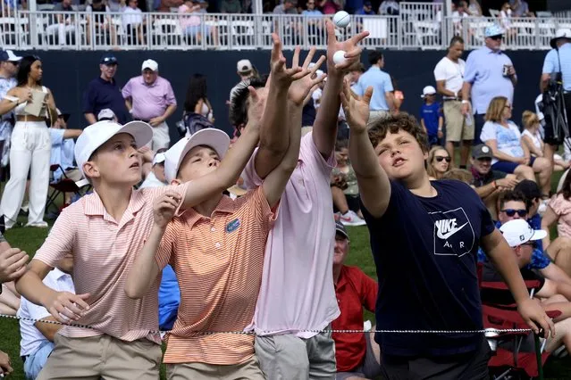 Young golf fans reach for a ball thrown by a player on the 17th green during the third round of The Players Championship golf tournament Saturday, March 16, 2024, in Ponte Vedra Beach, Fla. (Photo by Marta Lavandier/AP Photo)
