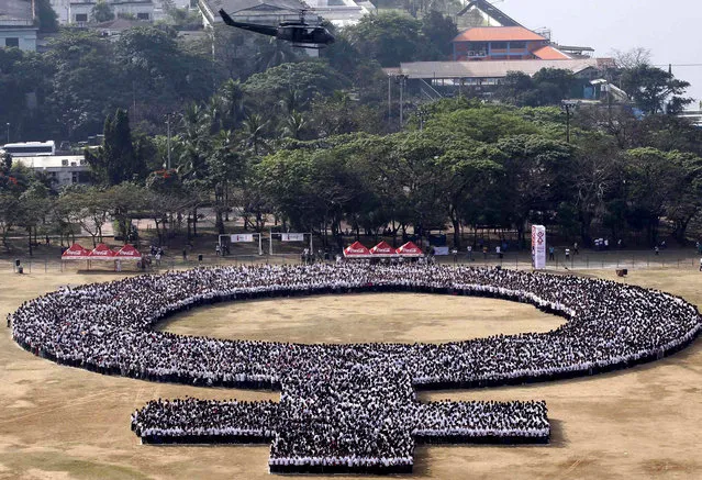 A military helicopter hovers over a female symbol formed by people, as part of celebrations for International Woman's Day in Manila March 8, 2014. On March 8, activists around the globe celebrate International Women's Day, which dates back to the beginning of the 20th Century and has been observed by the United Nations since 1975. (Photo by Romeo Ranoco/Reuters)