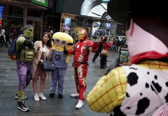 A tourist (2nd L) poses with two people dressed as Hulk and Iron Man, as another dressed as Woody from Toy Story takes their photo in Times Square, in New York, April 7, 2016. The assortment of costumed characters, painted naked women and ticket sellers who make the streets of New York's Times Square their office, catering to tourists, may soon be restricted after a City Council vote Thursday. (Photo by Rickey Rogers/Reuters)