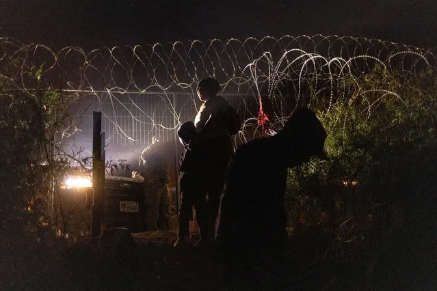 An Army National Guard soldier shines his flashlight towards migrants after others breached a razor wire laden fence  rom along the bank of Rio Grande in El Paso, Texas, on April 2, 2024. (Photo by Adrees Latif/Reuters)