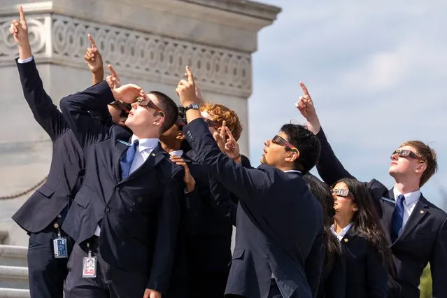 Senate pages wear eclipse glasses as they view the moon partially covering the sun during a total solar eclipse, in front of the U.S. Senate on Capitol Hill, Monday, April 8, 2024, in Washington. (Photo by Alex Brandon/AP Photo)
