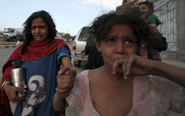 A girl cries next to her mother after fleeing from an air strike on an army weapons depot in Yemen's capital Sanaa May 11, 2015. (Photo by Mohamed al-Sayaghi/Reuters)