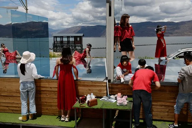 Tourists pose for photos on a mirror platform at a photo booth near Erhai Lake in Dali Bai Autonomous Prefecture, Yunnan province, China on June 15, 2019. (Photo by Tingshu Wang/Reuters)