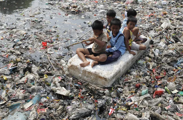 Children sitting on a makeshift raft play in a river full of rubbish in a slum area of Jakarta on September 19, 2012. (Photo by Enny Nuraheni/Reuters)