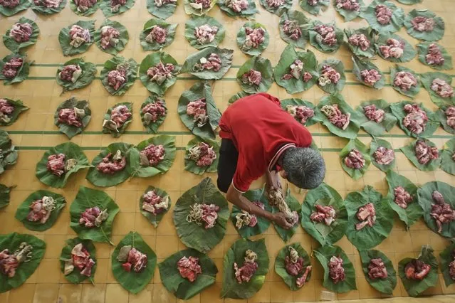 An Indonesian Muslim man places meat on leaves before distributing it during Muslim holiday of Eid al-Adha at a mosque in Yogyakarta, Indonesia, August 11, 2019. (Photo by Andreas Fitri Atmoko/Antara Foto via Reuters)