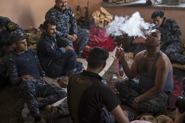 Federal policemen smoke a water pipe during a break before returning to fight against Islamic State militants, on the western side of Mosul, Iraq, Wednesday, March 29, 2017. (Photo by Felipe Dana/AP Photo)