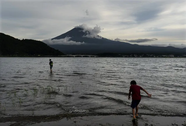 A boy walks into the water Tuesday, August 6, 2019, in Lake Kawaguchi with Mount Fuji in the background, west of Tokyo. (Photo by Jae C. Hong/AP Photo)