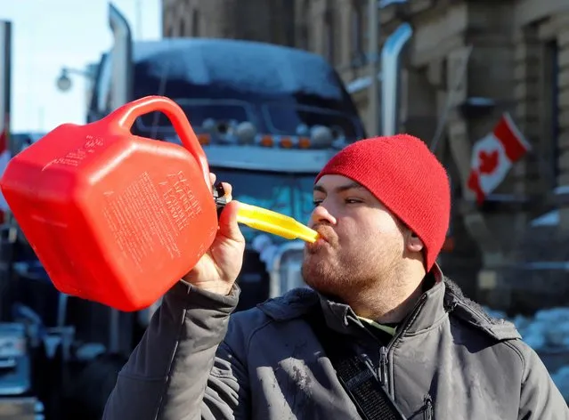 A person pretends to drink from a fuel can after police said they will be targeting the truckers' fuel supply as truckers and their supporters continue to protest coronavirus disease (COVID-19) vaccine mandates, in Ottawa, Ontario, Canada, February 7, 2022. (Photo by Patrick Doyle/Reuters)