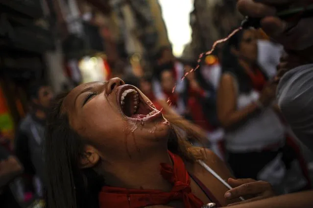 In this photo taken Wednesday, July 8, 2015, a woman has red wine poured into her mouth at the San Fermin Festival, in Pamplona, Spain. (Photo by Alvaro Barrientos/AP Photo)