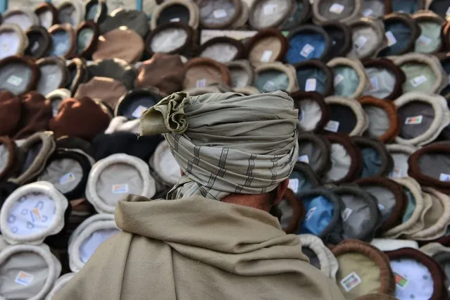 A man looks at hats in a market near the Pul-e Khishti mosque in Kabul on March 1, 2022. (Photo by Wakil Kohsar/AFP Photo)