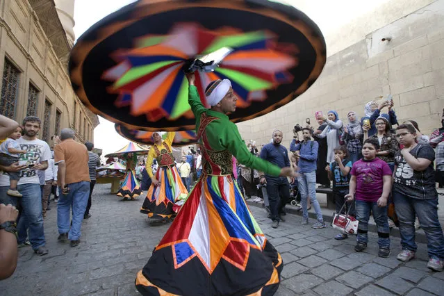 Whirling dervishes participate in The International Festival for Drums and Traditional Arts in El-Moez street in historical Fatimid Cairo, Egypt, Friday, April 21, 2017. The festival hosts teams from around 23 countries raising the slogan “Drums Dialogue for Peace” aiming at spreading tolerance and cultural awareness. (Photo by Amr Nabil/AP Photo)