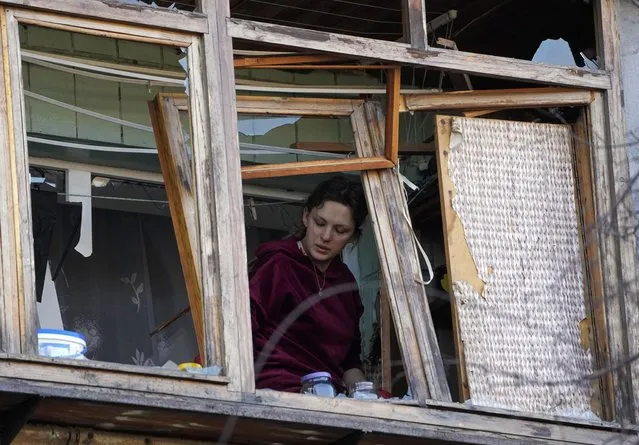 A women stands near a broken window in her apartment after a Russian bombing attack in Kyiv, Ukraine, Monday, March 14, 2022. (Photo by Efrem Lukatsky/AP Photo)