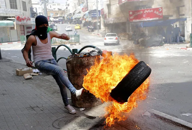 A Palestinian protester kicks a burning tire during clashes with Israeli troops in the West Bank city of Hebron 27 April 2017. Palestinians across the West Bank and East Jerusalem are in a general trade strike in solidarity with some 1500 Palestinian prisoners jailed in Israeli prisons for security offenses against Israelis. the prisoners started a hunger strike on 17 April protesting what they call inhumane treatment and restrictions in Israeli prisons. (Photo by Abed Al Haslhamoun/EPA)
