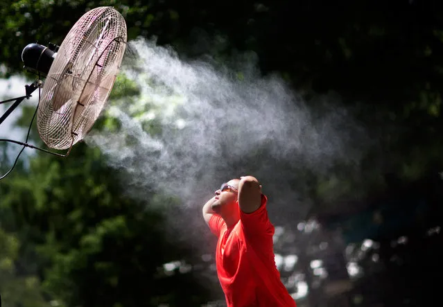 Carlos Ramirez, of West Palm Beach, Fla., cools off under a misting fan while visiting Zoo Atlanta, Wednesday, July 15, 2015, in Atlanta. Severe thunderstorms will be possible over the southern half of Georgia and eastern South Carolina as temperatures hover around the ninety degree mark. (Photo by David Goldman/AP Photo)