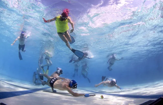 In this Friday, June 26, 2015 photo, players battle for the puck as a referee, above, watches during the underwater hockey national championships in Santa Clarita, Calif. (Photo by Mark J. Terrill/AP Photo)