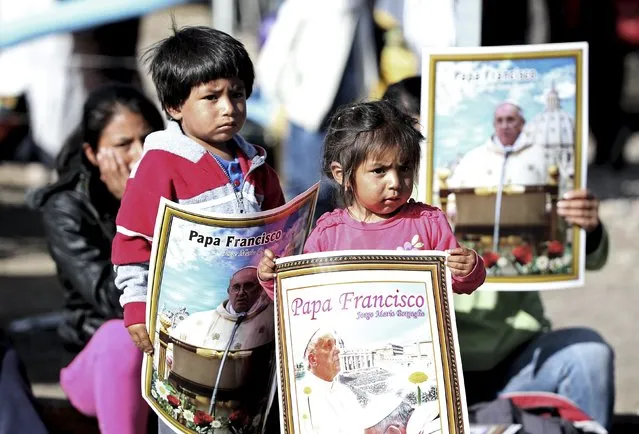 Children hold posters of Pope Francis before he arrives to visit the El Quinche Santuary near Quito, Ecuador, July 8, 2015. (Photo by Alessandro Bianchi/Reuters)