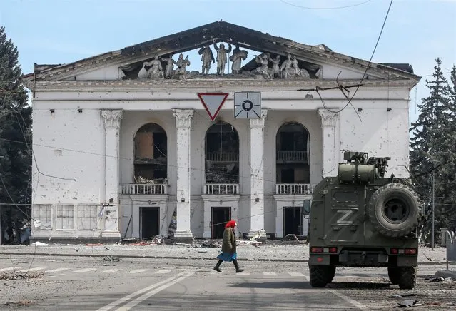 A woman walks next to an armoured vehicle of pro-Russian troops the building of a theatre destroyed in the course of Ukraine-Russia conflict in the southern port city of Mariupol, Ukraine on April 10, 2022. (Photo by Alexander Ermochenko/Reuters)