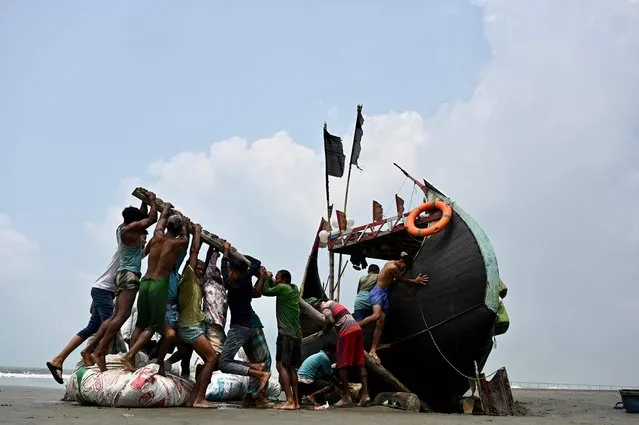 Fishermen try to lift a stranded boat after fishing from the Bay of Bengal in Teknaf on March 28, 2022. (Photo by Munir Uz Zaman/AFP Photo)