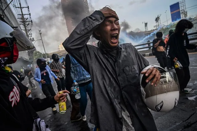 Anti-government protesters react to tear gas fired by riot police to disperse them on August 10, 2021 in Bangkok, Thailand. The clashes came after a weekend protest in which activists clashed with police, despite Covid-19 cases and deaths remaining at record highs. (Photo by Sirachai Arunrugstichai/Getty Images)