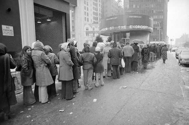 Despite sub-freezing temperatures and rain, a crowd waits in line outside the Paramount Theater in New York City February 4, 1974 for a showing of "The Exorcist." Theater operators in the 28 cities where the picture is showing report full houses, long lines and extra showings. (Photo by Ron Frehm/AP Photo)