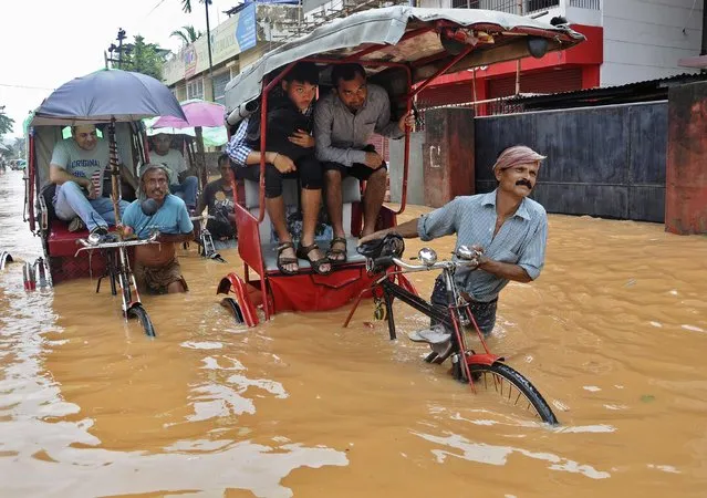 Rickshaw drivers wade through a flooded road after heavy rains swept through Guwahati, in the northeastern Indian state of Assam, on June 26, 2014. Seven people have been killed there in flash floods, landslides and heavy rainfall, local media reported Friday. (Photo by Utpal Baruah/Reuters)