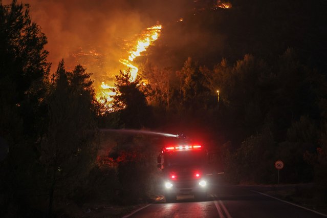 Firefighters try to extinguish a wildfire burning in Dionysos, Greece on August 12, 2024. (Photo by Alexandros Avramidis/Reuters)