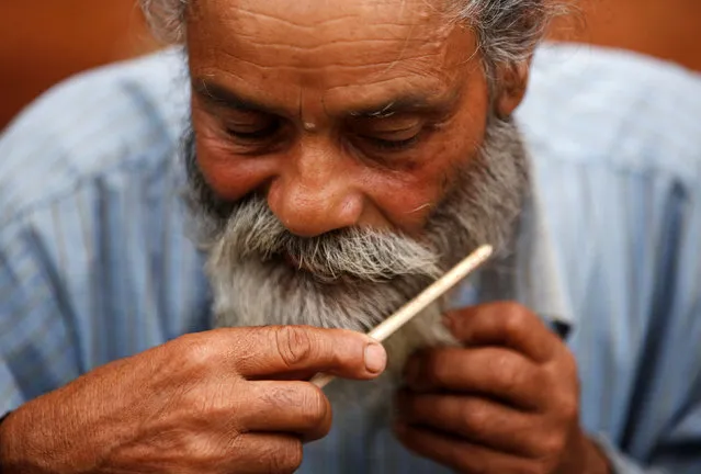 Durga Kami, 68, who is currently studying tenth grade at Shree Kala Bhairab Higher Secondary School, combs his beard, as he gets ready for school in Syangja, Nepal, June 5, 2016. Kami has promised his classmate Sagar Thapa that he will cut his beard off if he passes tenth grade. (Photo by Navesh Chitrakar/Reuters)