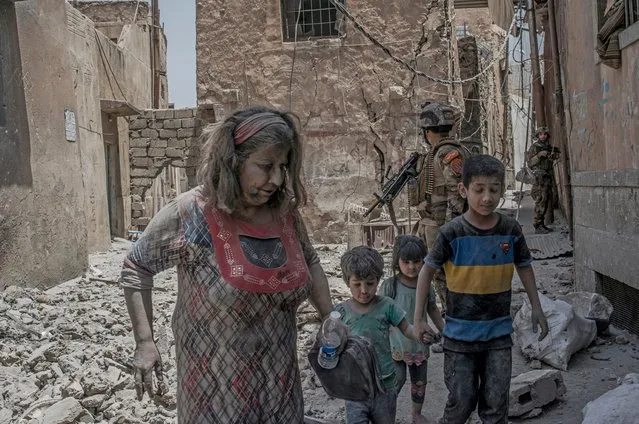 An Iraqi woman and her children flee the Old City district where heavy fighting continues on July 2, 2017 in Mosul, Iraq. Iraqi forces continue to encounter stiff resistance from Islamic State with improvised explosive devices (IEDs), car bombs, suicide bombers, heavy mortar fire and snipers hampering their advance. (Photo by Martyn Aim/Corbis via Getty Images)