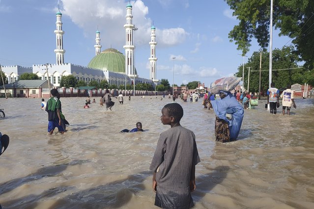 People walk through floodwaters following a dam collapse in Maiduguri, Nigeria, Tuesday September 10, 2024. (Photo by Joshua Olatunji/AP Photos)