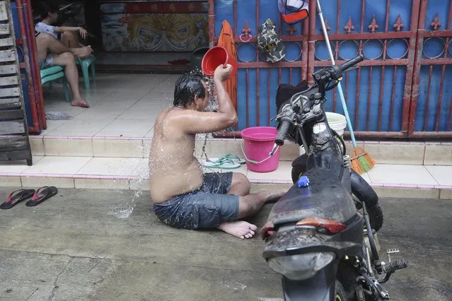 A man takes a shower in front of his flood-damaged house in Jakarta, Indonesia, Sunday, January 5, 2020. (Photo by Tatan Syuflana/AP Photo)