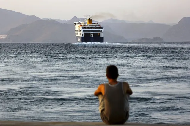 A Bangladeshi migrant, pending temporary documentation, watches from the port of Kos, Greece, a ferry bound for the port of Piraeus near Athens August 10, 2015. (Photo by Yannis Behrakis/Reuters)