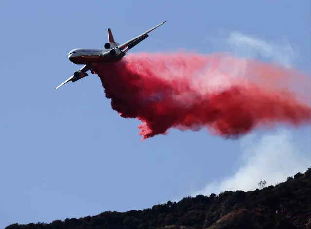 A firefighting plane makes a retardant drop on a hill near a wildfire in Azusa, Calif., Monday, June 20, 2016. (Photo by Nick Ut/AP Photo)