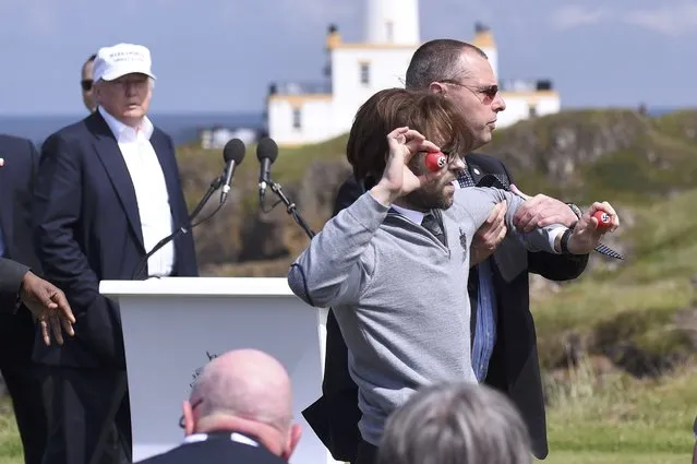 A man is removed by a security guard as he causes a disturbance during a speech by Republican presidential candidate Donald Trump (L), at his Turnberry golf course, in Turnberry, Scotland, Britain June 24, 2016. (Photo by Clodagh Kilcoyne/Reuters)