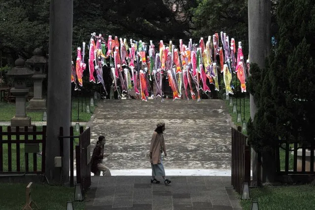  Local tourists walk past Japanese Koinobori, Japanese carp-shaped streamers, at the entrance of the Taoyuan Martyrs' Shrine and Cultural Park during a festival on June 17, 2022. (Photo by Sam Yeh/AFP Photo)