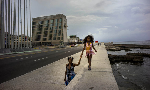 A girls holds her mother's hand, as she walks on the Malecon sea wall, past the the US embassy in Havana, Cuba, Tuesday, August 11, 2015. The embassy will hold a historic ceremony on Friday, Aug. 14 to raise the U.S. flag, to mark the reopening of the embassy on Havana’s historic waterfront. (Photo by Ramon Espinosa/AP Photo)