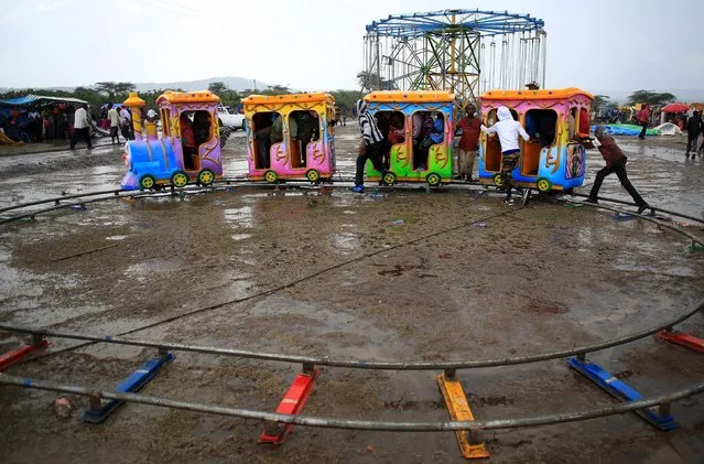 Children play with an amusement train ride during heavy rain during the Maralal Camel Derby, Kenya, August 15, 2015. (Photo by Goran Tomasevic/Reuters)