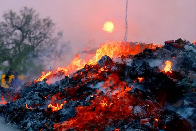 Flames rise during the incineration of seized illegal drugs to mark the International Day against Drug Abuse in Lahore, Pakistan, 26 June 2014. Pakistani law enforcement agency burnt a large quantity of narcotics and alcohol that was seized from different parts of the country, on 26 June, to mark the international day against drug abuse. (Photo by Rahat Dar/EPA)