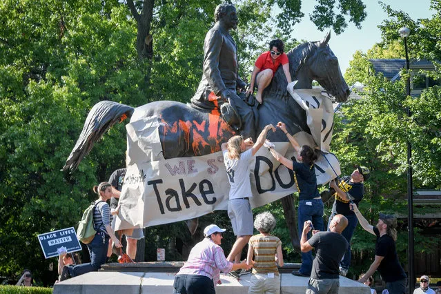 Members of a racial justice organization prepare to hang a banner, reading “Louisville, Take It Down” on a monument to Confederate soldier John B. Castleman in Louisville, Ky., August 19, 2017. (Photo by Bryan Woolston/Reuters)