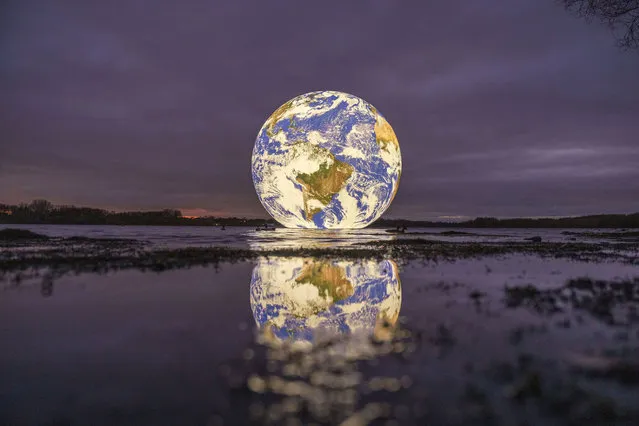 Artist Luke Jerram's new “Floating Earth” Debuts In Wigan on November 18, 2021 in Wigan, England. The floating Earth will hover over Pennington Flash for 10 days from November 19, as part of a celebration of Wigan and Leigh's watercourses. It is the first time one of Jerram's globes has been floated on an open expanse of water. (Photo by Christopher Furlong/Getty Images)
