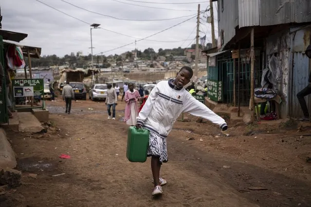 A girl carries a container of water back to her house in the Kibera neighborhood of Nairobi, Kenya Sunday, August 14, 2022. (Photo by Ben Curtis/AP Photo)